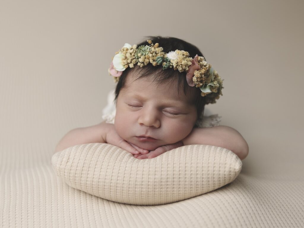Niña bebé recién nacida apoyada sobre un cojín